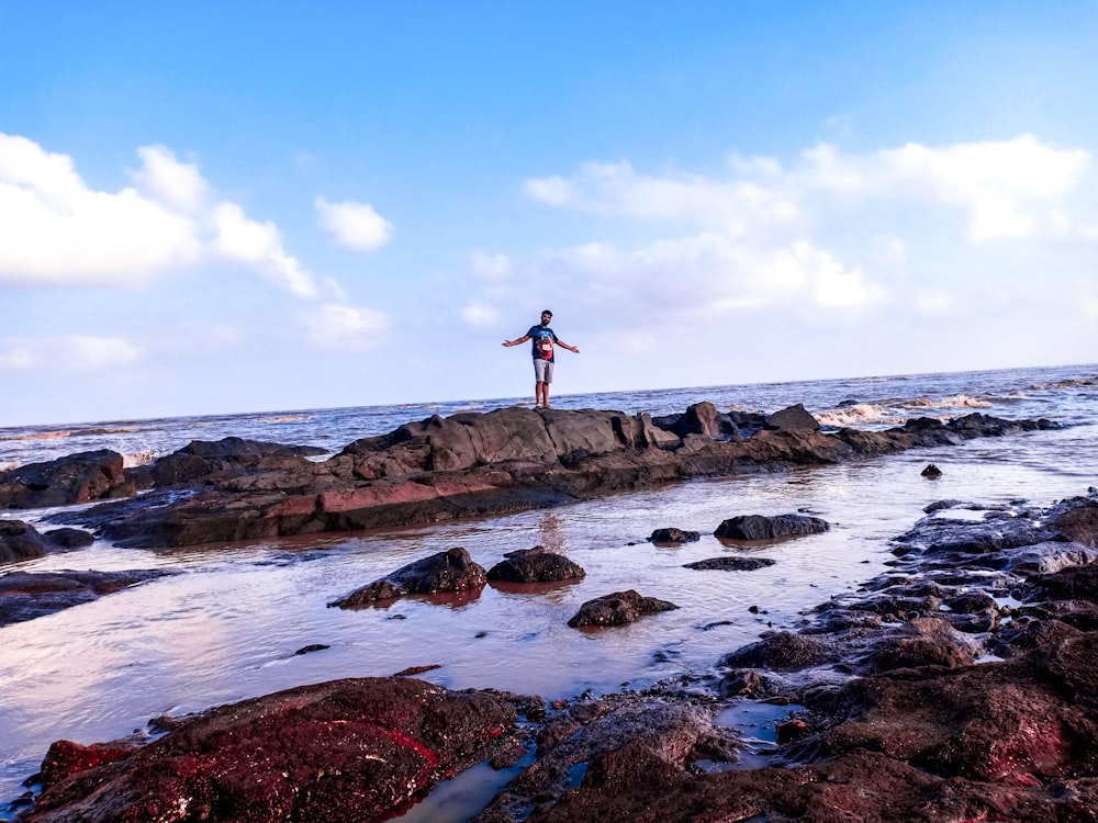 man standing on rock near body of water