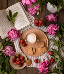 A pastel cookbook open on a pastel pink table with fresh berries around.