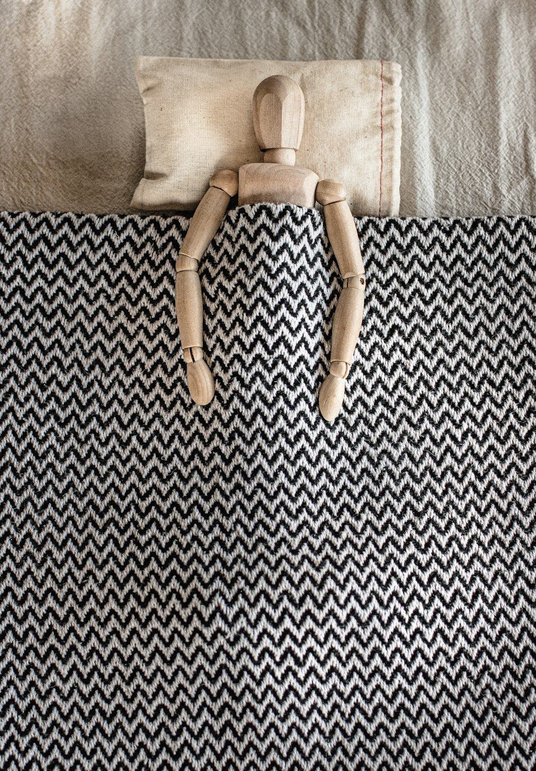 gray wooden mannequin lying on bed