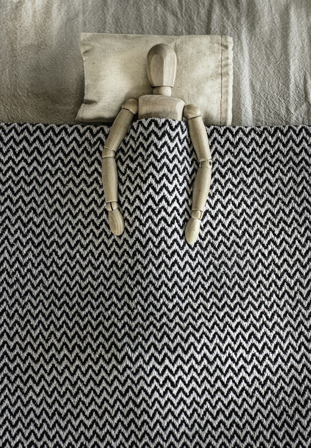 gray wooden mannequin lying on bed