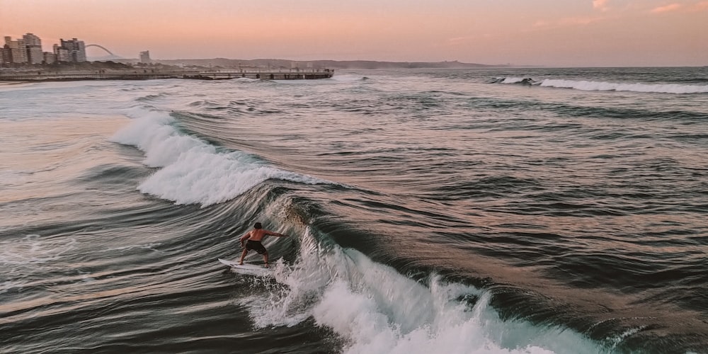 homem montando prancha de surf sob céu azul claro