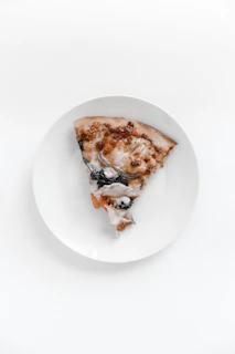 Slices of pizza arranged elegantly on a modern white plate with a drizzle of olive oil