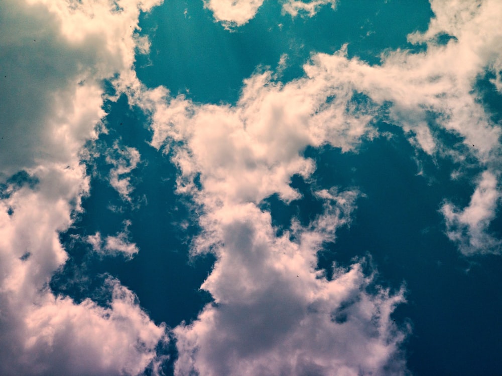 a plane flying through a cloudy blue sky