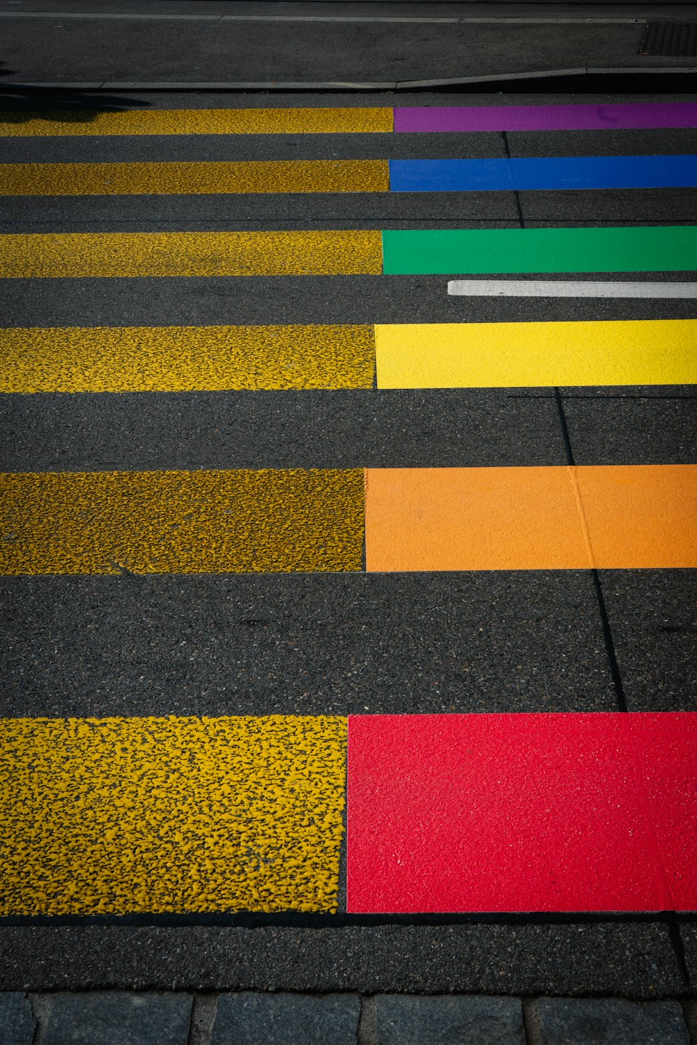 a crosswalk painted in different colors of yellow, red, green, blue,