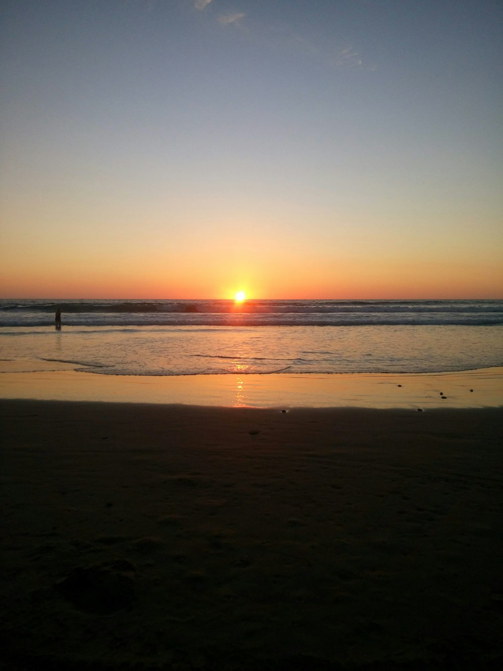 a person walking on the beach at sunset