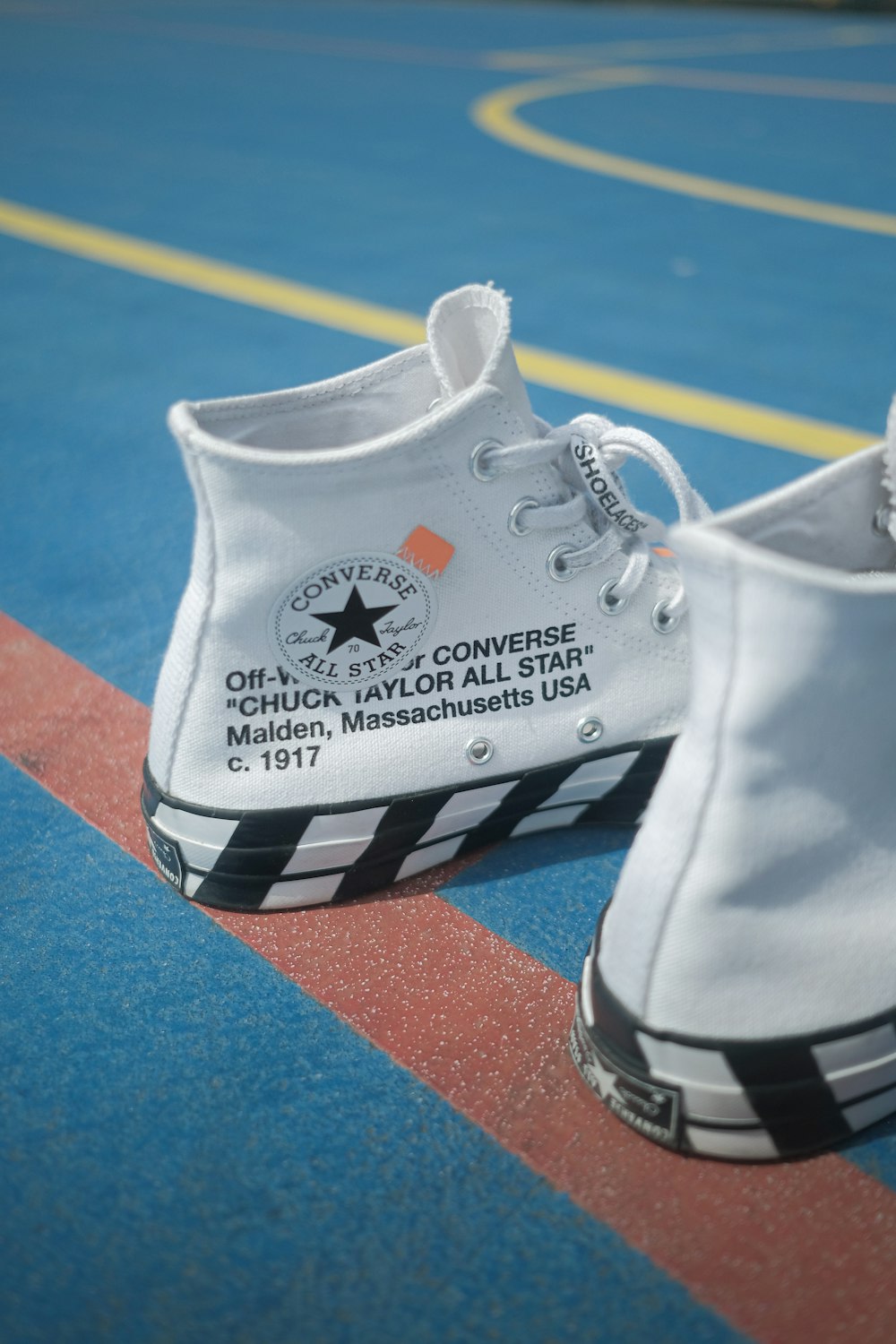 a pair of white converse sneakers on a basketball court