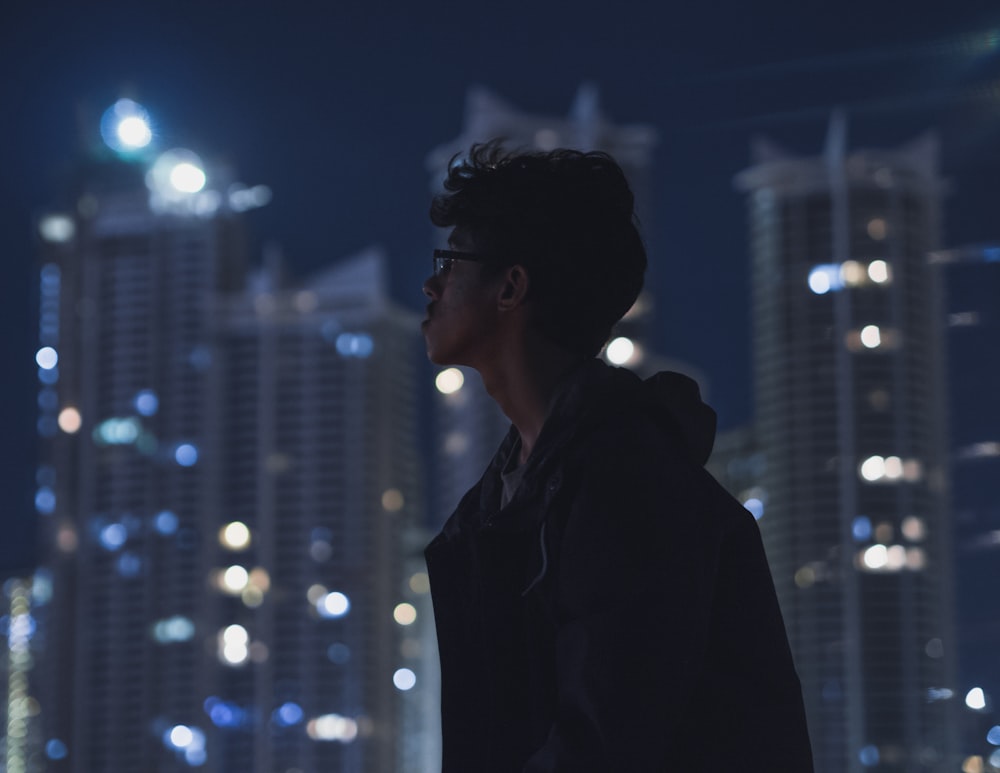 a man standing in front of a city at night