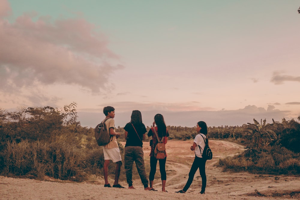 four person standing across green trees