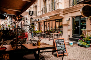 A cozy café terrace on a cobblestone street with travelers enjoying coffee and conversation.
