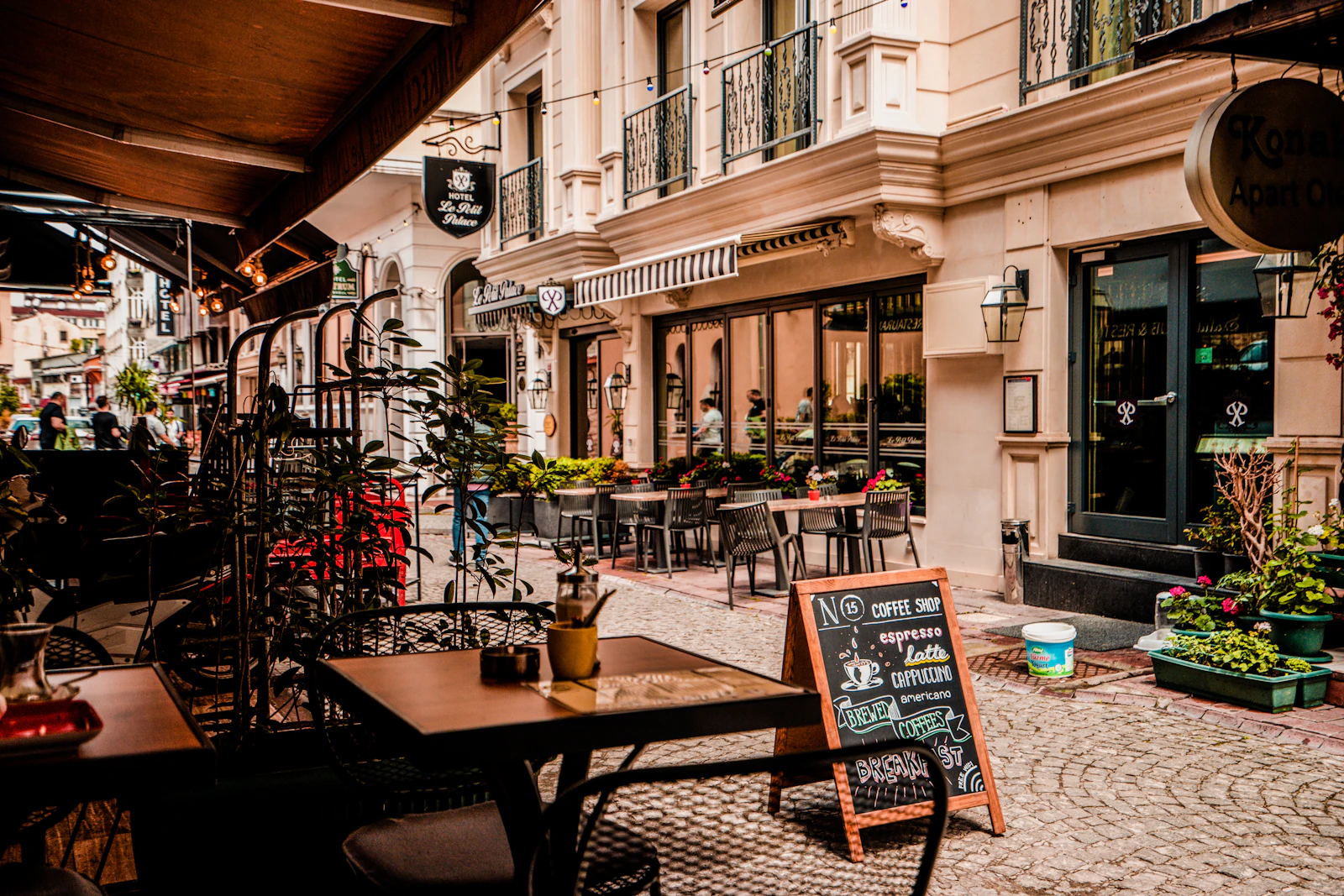 Frente de un café con mesas en la vereda en una calle empedrada
