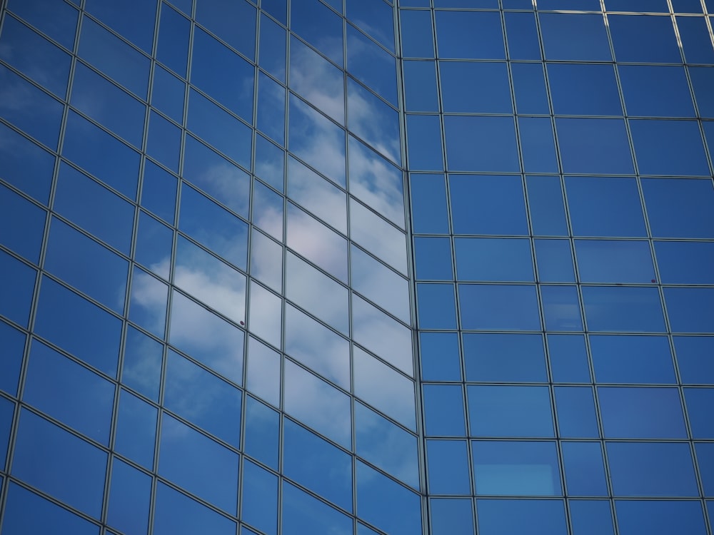a blue sky and clouds reflected in a glass building