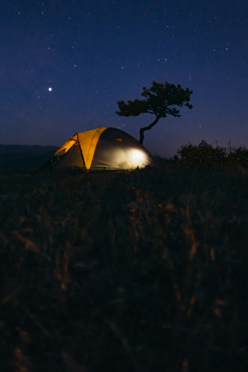 gray and yellow camping tent in the middle of grass field camping during nightime