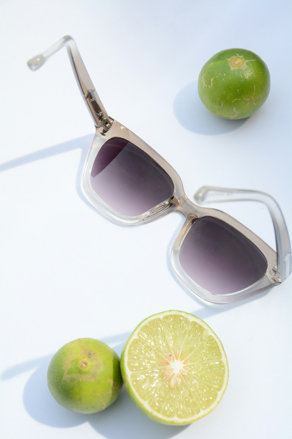 Flat-Lay-Fotografie von Sonnenbrillen und geschnittenen Calamondin-Früchten