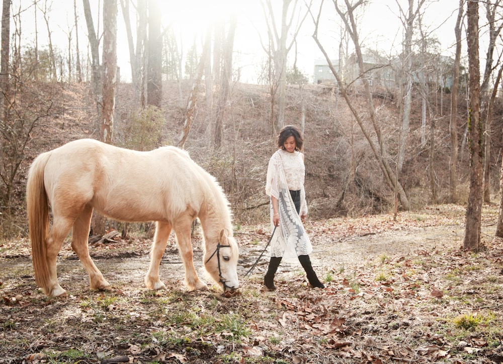 woman wearing black boots besides white horse