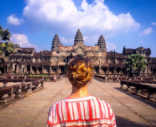 woman wearing red and white striped blouse standing in front of temple in Angkor Wat Cambodia