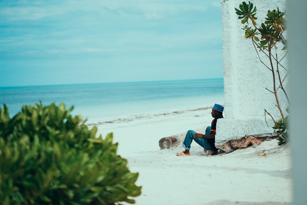shallow focus photo of person sitting on seashore during daytime