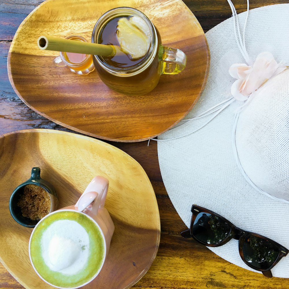 white ceramic mug beside black wayfarer sunglasses