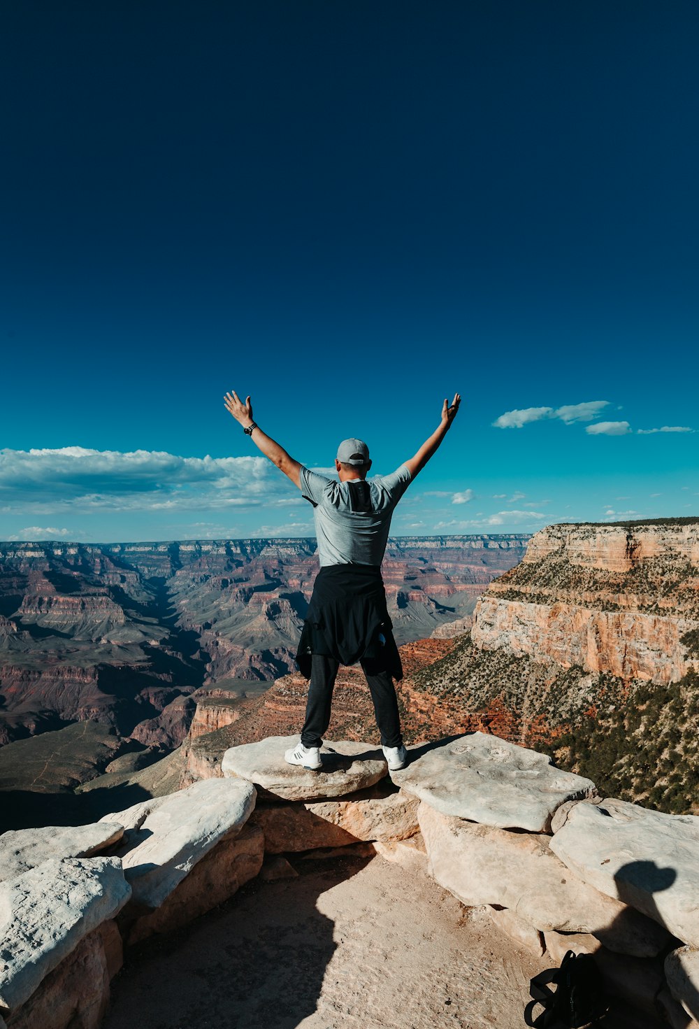 man wearing gray crew-neck shirt standing on mountain edge