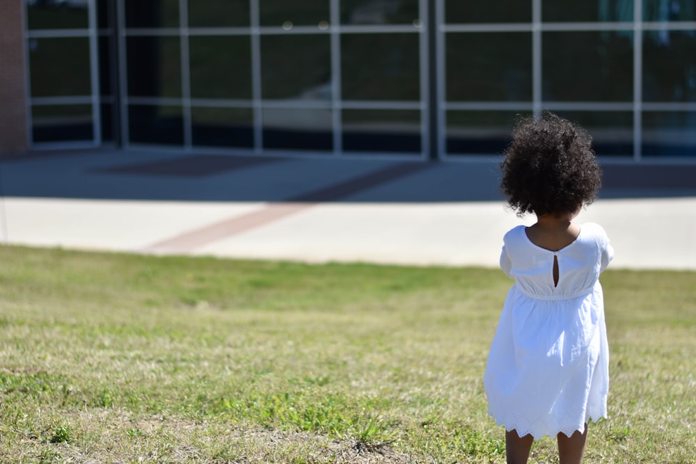 girl wearing white dress standing on grass