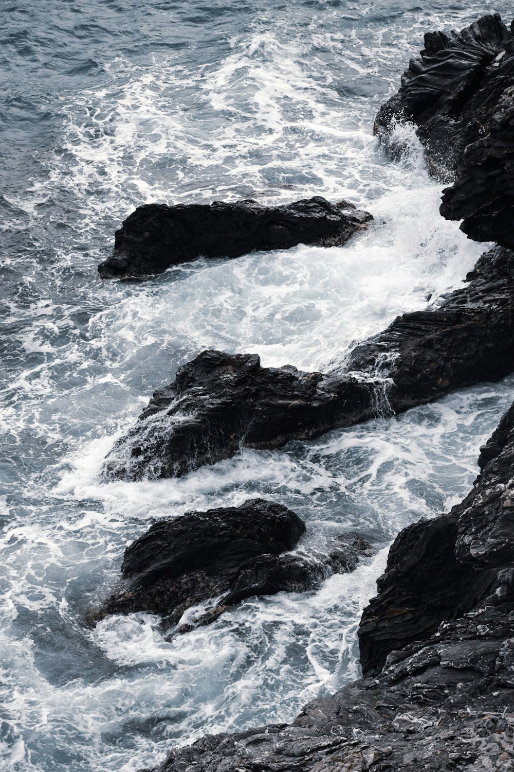 black rocks at beach during daytime