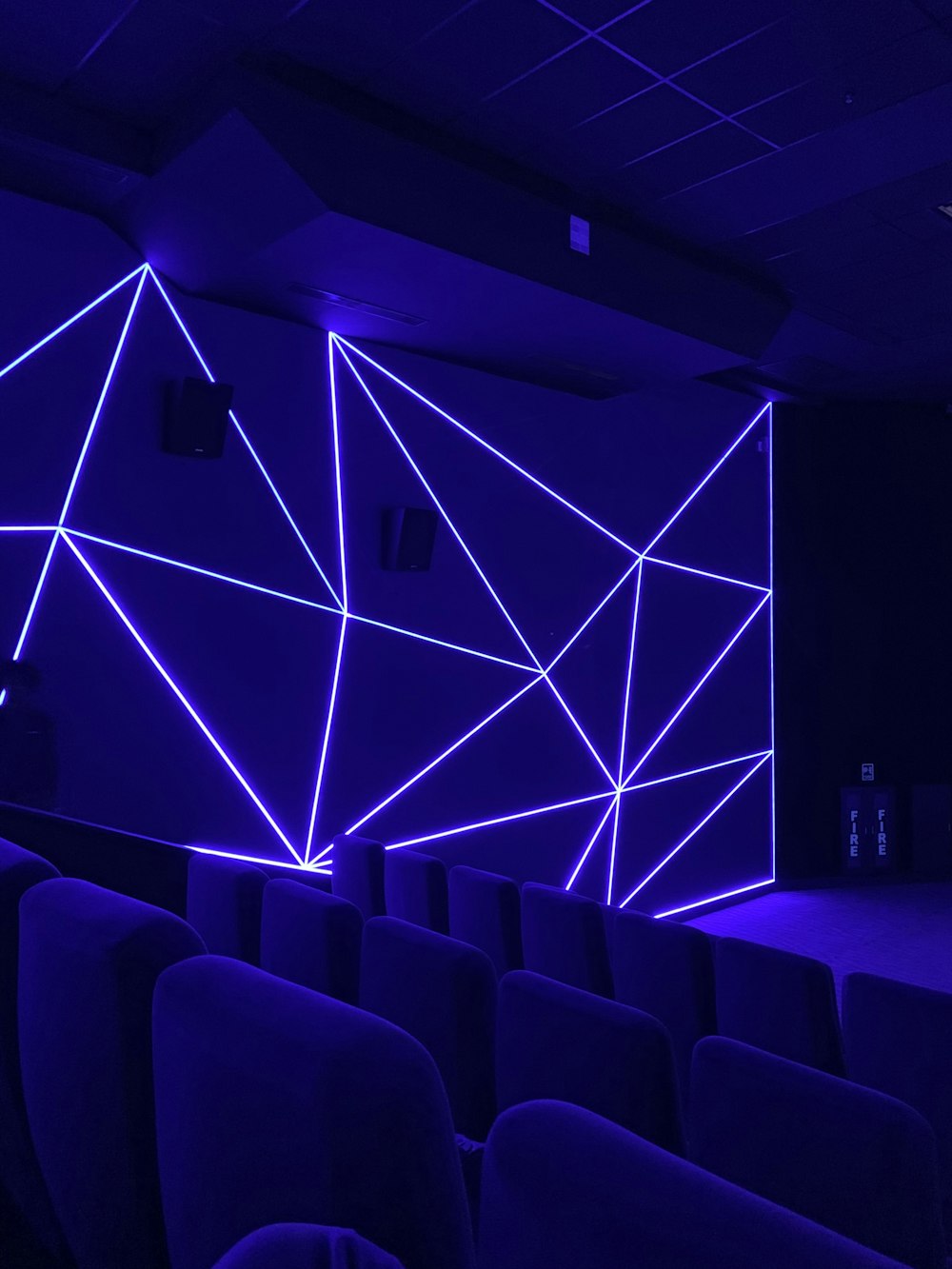 an empty auditorium with blue lighting and a projector screen