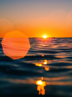 A vibrant sunset over the ocean with surfers catching the last waves of the day.