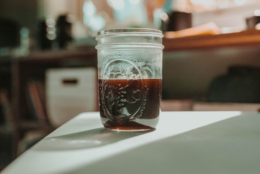 half empty clear glass jar on white surface