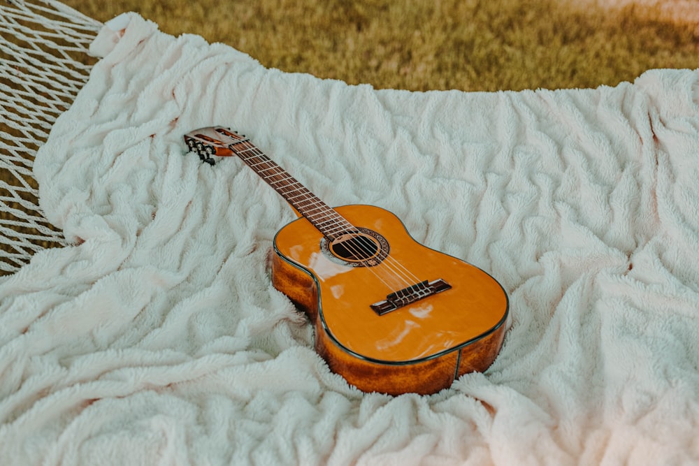 Guitarra clásica marrón sobre manta blanca