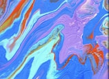 Vibrant abstract patterns in swirling, fluid formations with a dominant presence of blue, purple, and red colors. The composition is filled with smooth, flowing curves and contrasting lines, creating a mesmerizing visual effect reminiscent of liquid or watercolor art.