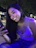 A woman smiling while chatting on WhatsApp with cricket stadium lights in the background.