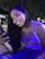 A woman smiling while chatting on WhatsApp with cricket stadium lights in the background.