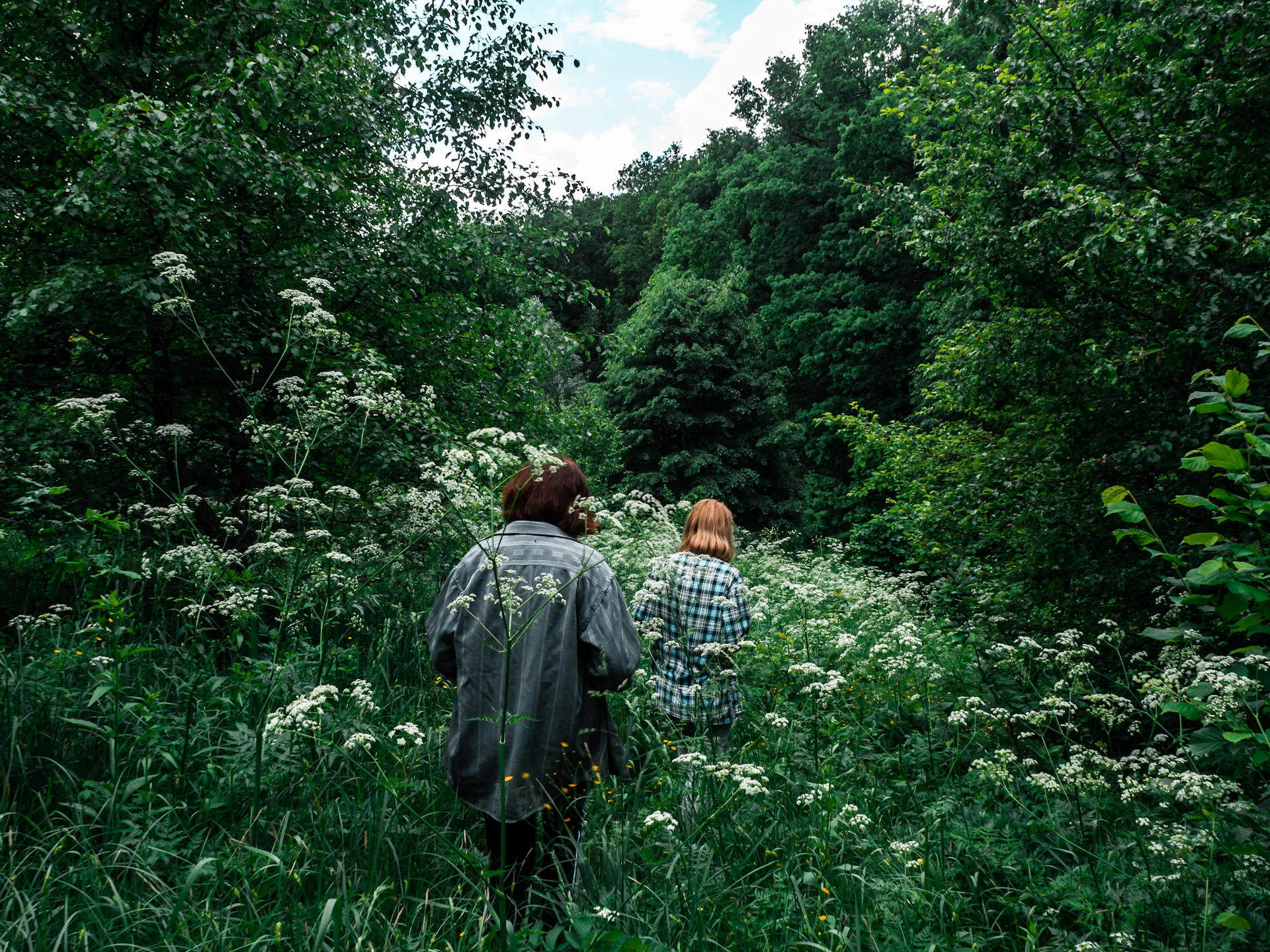 Couple hiking through lush green rainforest with vibrant tropical flowers around