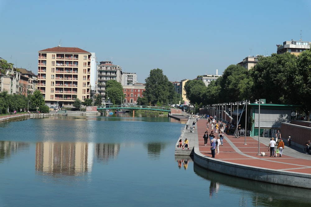 people walking on pathway near concrete buildings under blue skies