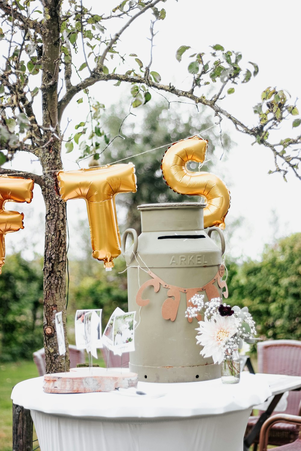 a table topped with a vase filled with gold balloons