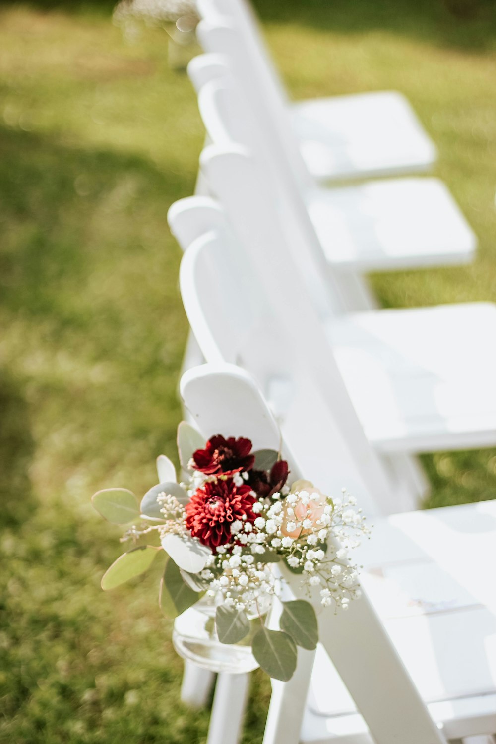a row of white chairs sitting on top of a lush green field