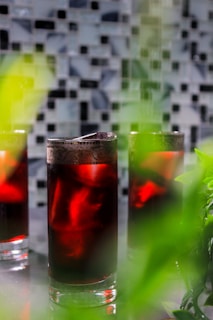 Refreshing drinks lineup showcasing deep reds and greens in sleek glassware against a charcoal black backdrop