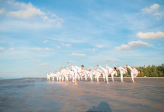 Students practicing karate moves outdoors under the clear sky.