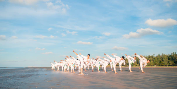Students practicing karate moves outdoors under the clear sky.