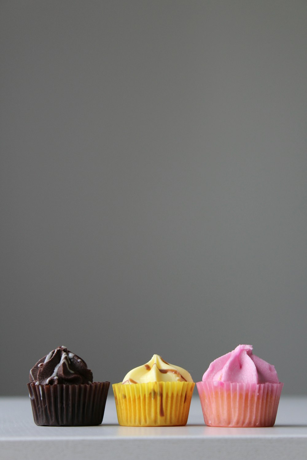 three cupcakes on white surface