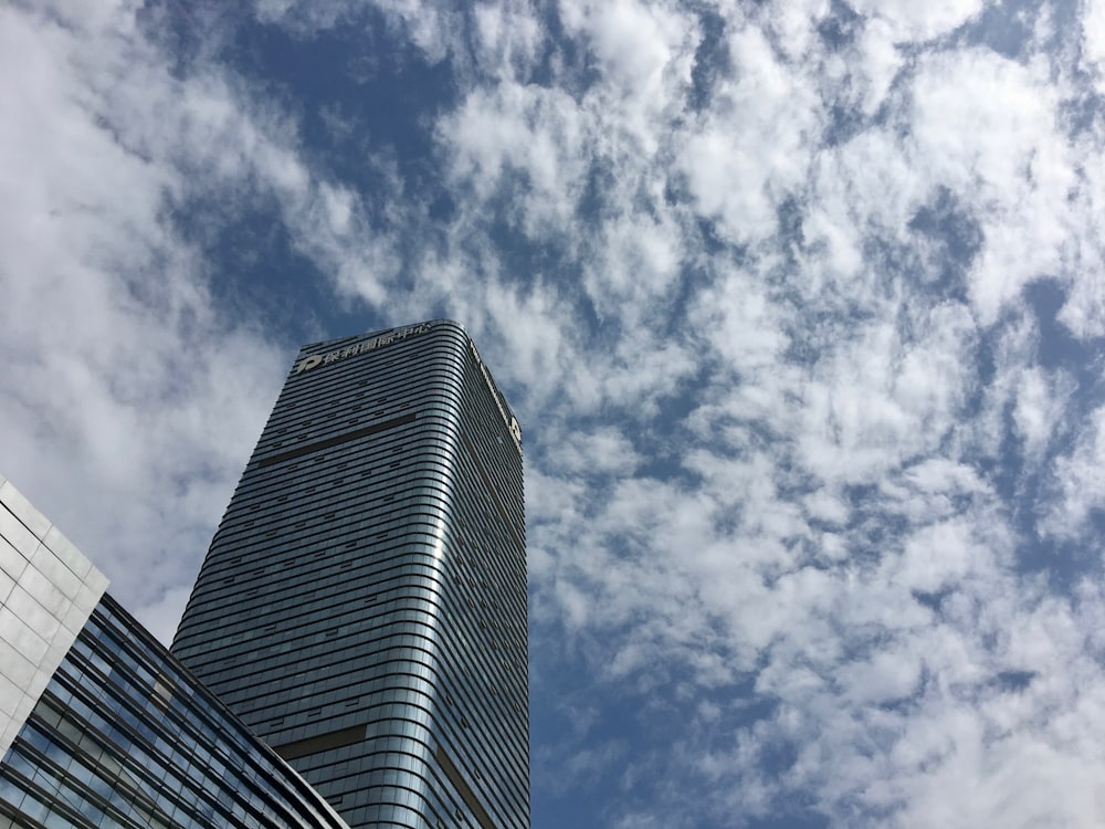 gray glass walled building under white and blue skies