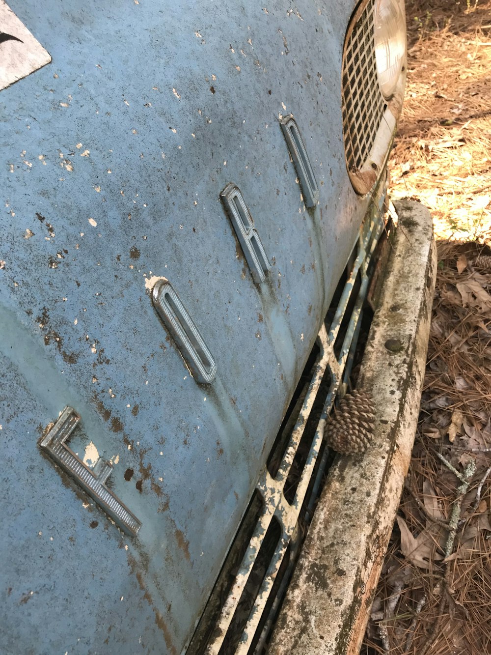 an old blue car is sitting in the woods