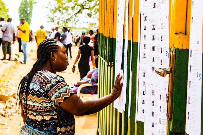 African woman checking a voter registration list at a polling station