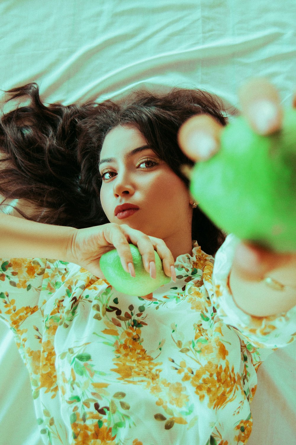 lying person holding two fruits on both hands