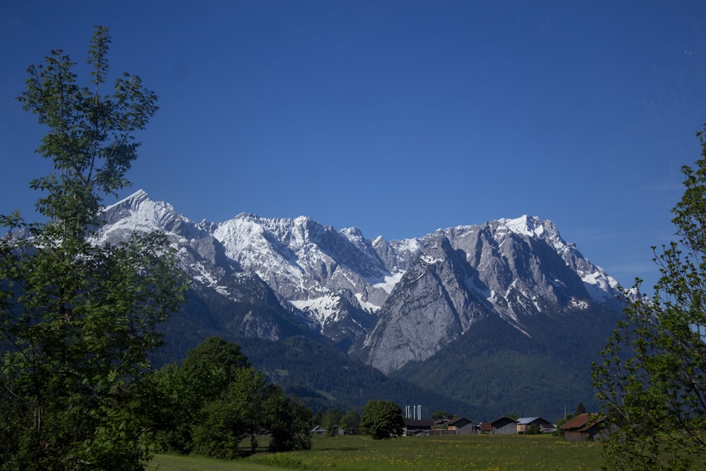 white snow capped grey mountain range with houses in valley below