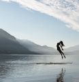 silhouette of jumping woman on raft in middle of lake