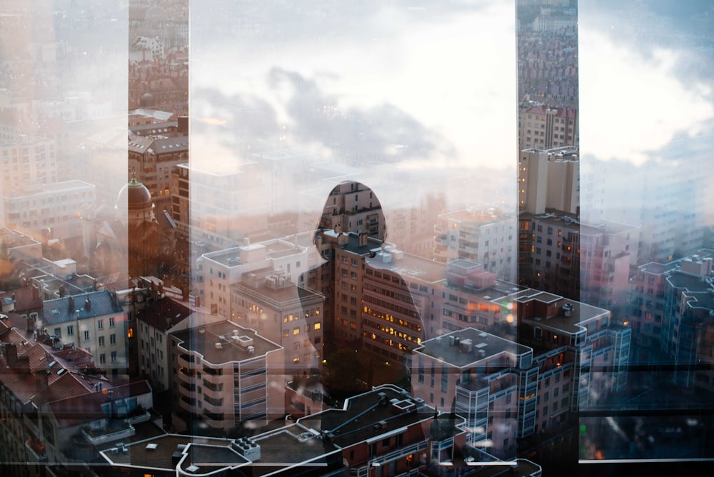 Riflessione della donna in piedi davanti al pannello di vetro di fronte a grattacieli e edifici medi