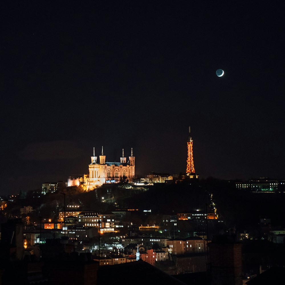 crescent moon over lighted city skyline