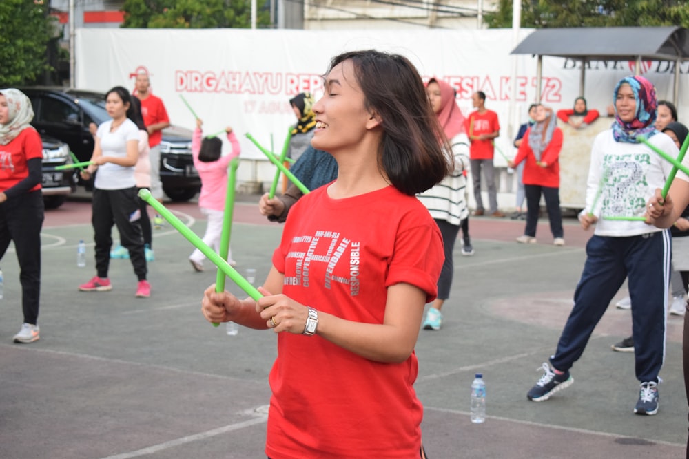 woman in orange crew-neck t-shirt holding green sticks