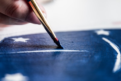 Close-up of a painter’s brush carefully applying vibrant blue paint on a home’s front door.