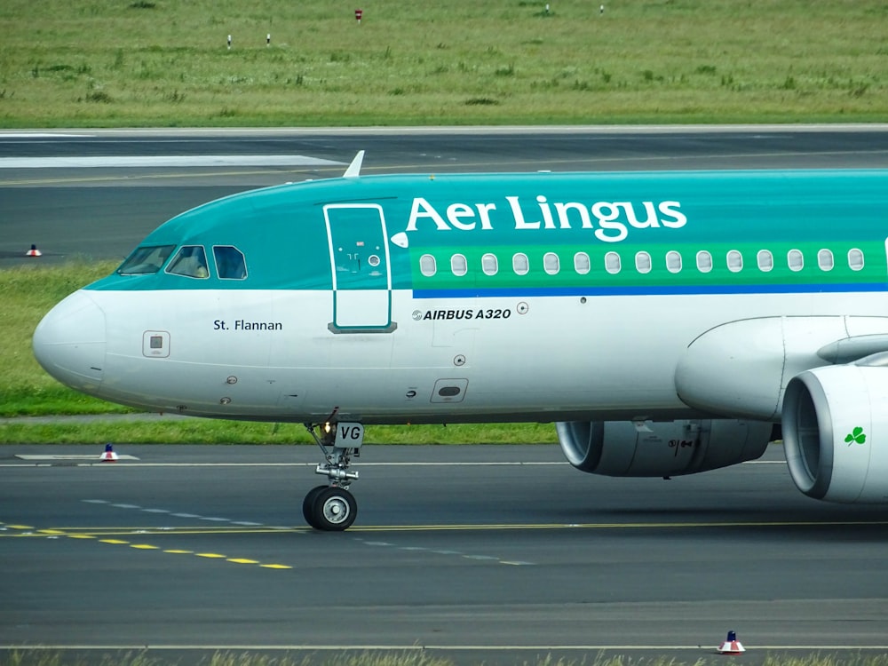 green and white Aer Lingus plane landing on railway